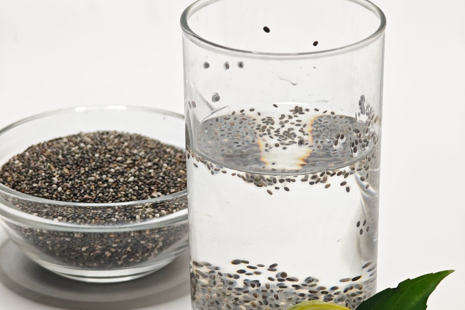 Glass of chia seed water next to a small bowl of dry chia seeds