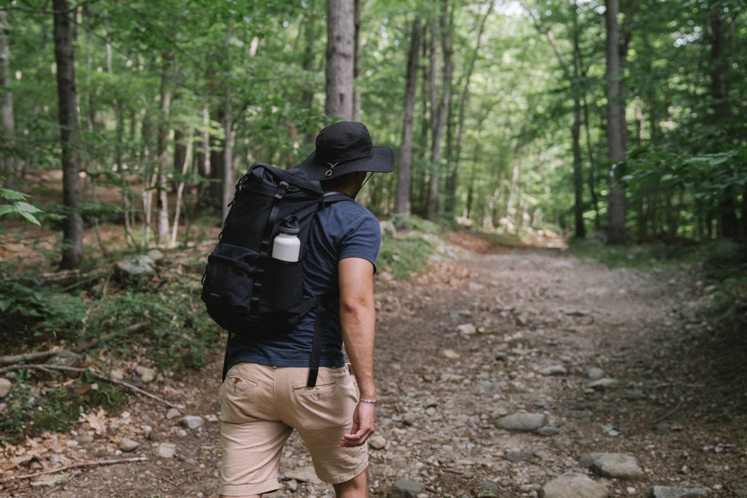 man rucking uphill with a backpack to burn more calories