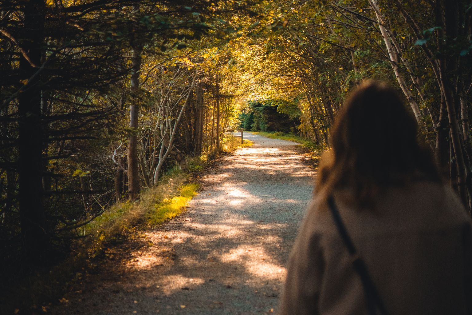 woman walking a tree-lined park path to stop overthinking